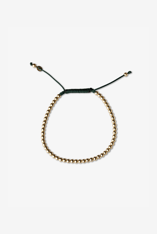 Pulseira em algodão verde escuro com bolinhas douradas.