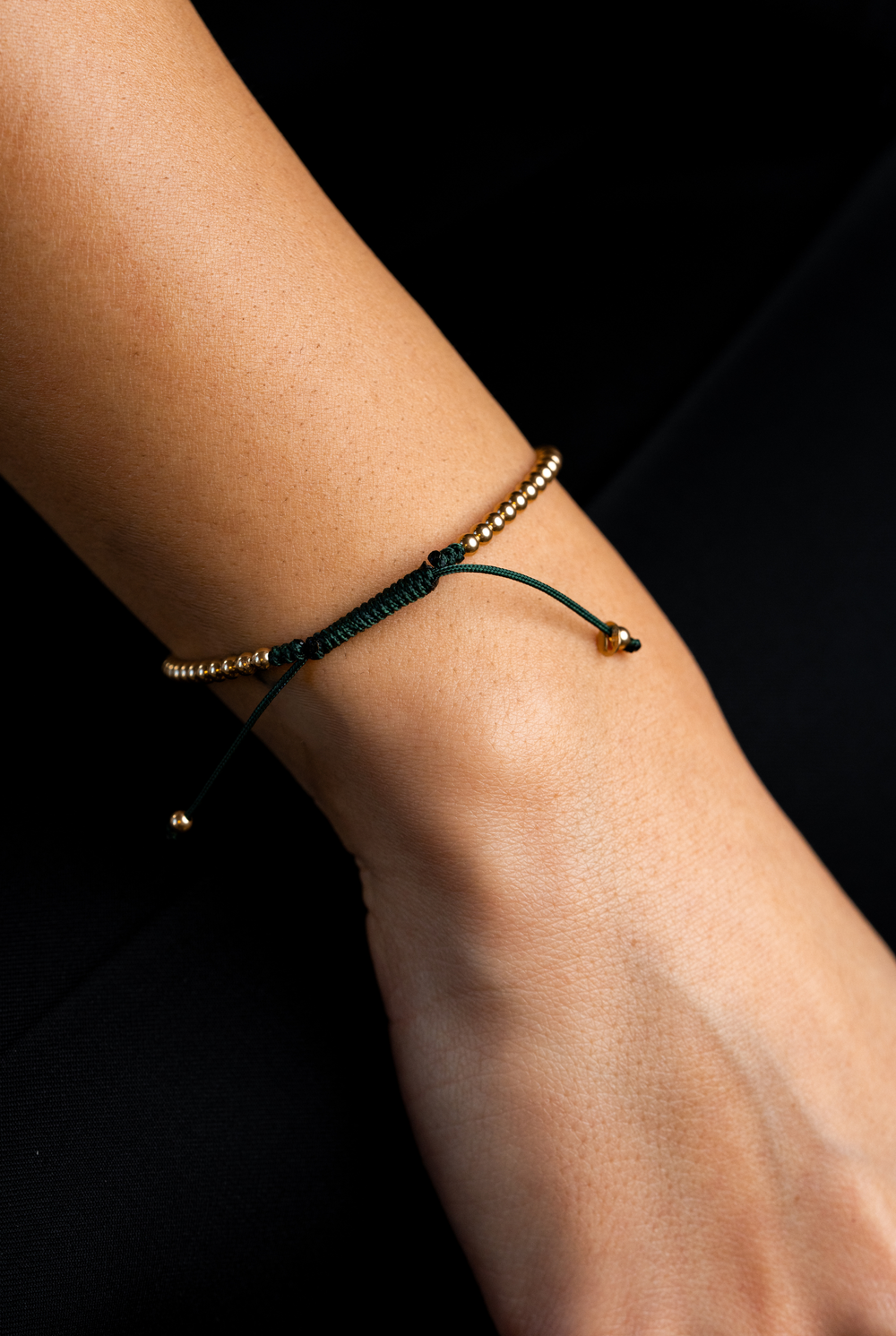 Pulseira em algodão verde escuro com bolinhas douradas.